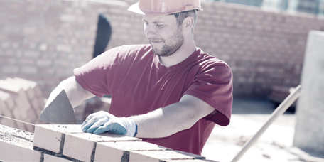 Muratore che costruisce un muro di mattoni in un cantiere